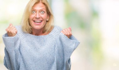 İzole arka plan üzerinde kutluyor kış kazak giyen orta yaş sarışın kadın şaşırttı ve başarı için kaldırdı kollarını açarak hayret ve gözleri açık. Kazanan kavramı.