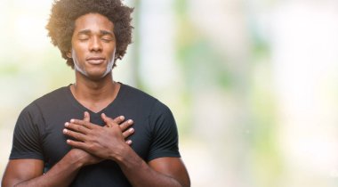 Afro Amerikalı adam ile gülümseyen izole arka plan üzerinde kapalı gözler ve yüzünde minnettar jest ile göğüs üzerinde eller. Sağlık kavramı.