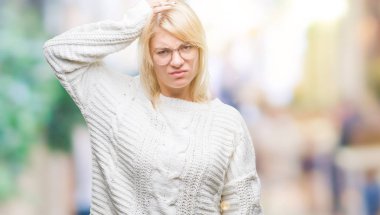 Genç güzel sarışın kadın giyiyor kış kazak ve izole arka plan üzerinde gözlük yanıltır ve soru hakkında merak ediyorum. Şüphe, kafasına el ile düşünme ile belirsiz. Dalgın kavramı.