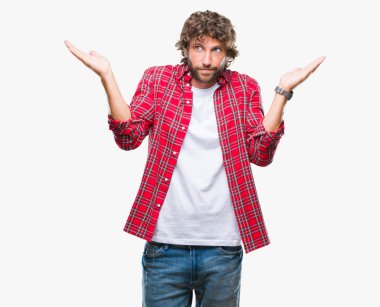 Yakışıklı İspanyol modeli adam izole arka plan clueless ve şaşkın bir ifadeyle kollar ve eller kaldırdı. Şüphe kavramı.