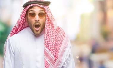 Keffiyeh izole arka plan korkuyor ve şok sürpriz ifade, korku ve heyecan yüz üzerinde giyen genç yakışıklı adam.
