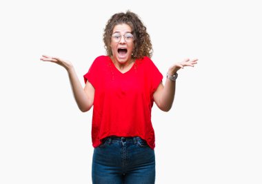 Güzel esmer kıvırcık saçlı Genç kız üzerinde gözlük takan deli kutluyor arka plan izole ve çığlık kaldırdı ve açık gözleri heyecanlı silah ile başarı için hayrete düşürdü. Kazanan kavramı