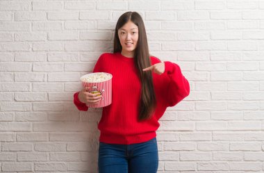 Sürpriz yüz işaret parmağı kendine pop Mısır yeme tuğla duvarın üzerinden Genç Çinli kadın