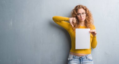 Gri grunge genç Kızıl saçlı kadın duvar kızgın yüzü, eksi işareti aşağı antipati başparmak ile gösterilen, ret kavramı ile boş kağıt levha holding