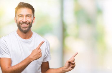 Gülümseyen ve iki elleri ve parmakları ile tarafına işaret kamera bakarak izole arka plan yetişkin İspanyol adam.