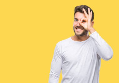 Genç yakışıklı adam gülümsüyor, parmakları ile mutlu yüz üzerinden seyir göz el ile ok jest yapıyor izole arka plan üzerinde.