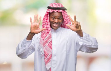 Geleneksel keffiyeh gösterilen ve parmakları ile işaret izole arka plan üzerinde giyen genç Arapça Afrika adam kendinden emin ve mutlu gülümseyerek süre sekiz numara.