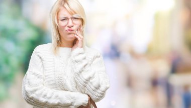 Diş ağrısı veya dişlerde dişlerle ilgili hastalık nedeniyle ağız acı ifadesi ile el ile dokunmak izole arka plan üzerinde kış kazak ve gözlük giyen genç güzel sarışın kadın. Diş hekimi kavramı.