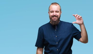 İzole arka plan gülümseyen ve boyutu işaret parmaklı ararken ve kamera işi el ile kendinden emin eller genç beyaz hipster adam. Ölçü kavramı.