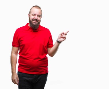 Yüzünde kocaman bir gülümseme ile izole arka plan üzerinde kırmızı gömlek giymiş genç beyaz hipster adam kameraya bakarak yan el ve parmak ile işaret.
