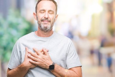 Orta yaş üst düzey ağarmış adam ile gülümseyen izole arka plan üzerinde kapalı gözler ve yüzünde minnettar jest ile göğüs üzerinde eller. Sağlık kavramı.