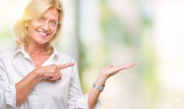 Orta yaş sarışın iş kadını üzerinden hayran ve el ile sunulması ve parmak ile işaret ederken kameraya gülümseyen izole arka plan.