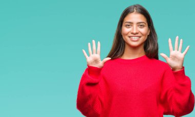 Genç güzel Arap kadın giyiyor kış kazak gösterilen ve parmakları ile işaret izole arka plan üzerinde kendinden emin ve mutlu gülümseyerek süre on numara.