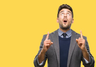 Genç yakışıklı iş adamı izole arka plan üzerinden hayran ve yukarıya bakıp parmakları ile işaret şaşırttı ve silah kaldırdı.