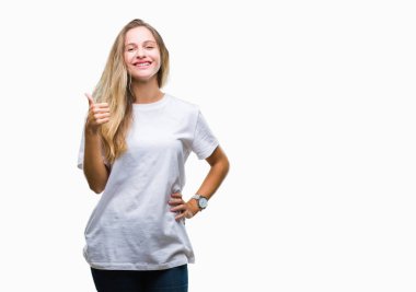 Hareketi el ile mutlu yaşasın yapıyor izole arka plan üzerinde rahat beyaz t-shirt giyen genç güzel sarışın bir kadın. Kameraya bakarak başarı gösteren ile ifade onaylama.