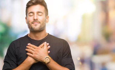 Yakışıklı delikanlı ile gülümseyen izole arka plan üzerinde kapalı gözler ve yüzünde minnettar jest ile göğüs üzerinde eller. Sağlık kavramı.