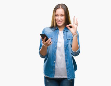 Genç güzel beyaz kadın texting parmak, mükemmel sembolü ile ok işareti yapıyor izole arka plan üzerinde Smartphone kullanarak ileti gönderme