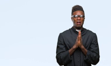 Yalvarıyor ve umut ifade yüzünde çok duygusal ve endişe ile birlikte elleriyle dua izole arka plan genç Afro-Amerikan rahip adam. Bağışlanmak. Din kavramı.