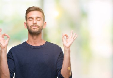 Genç yakışıklı adam giyen kış kazak izole arka plan üzerinde dinlenmek ve gülümseyen gözlerle parmak ile meditasyon jest yapıyor kapalı. Yoga kavramı.