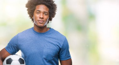 Acımak yüz ciddi düşünüyorum üstünde kendine güvenen bir ifade ile izole arka plan üzerinde futbol topu tutan Afro Amerikalı adam