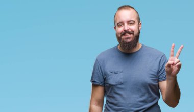 Mutlu yüz zafer işareti yaparken kameraya göz kırpıyor ile gülümseyen izole arka plan Genç beyaz hipster adam. İki numaralı.