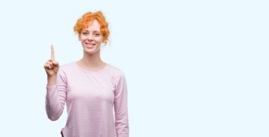 Ve parmak gülümseyen süre bir numara ile kendinden emin ve mutlu yukarıyı gösteren genç Kızıl saçlı kadın.
