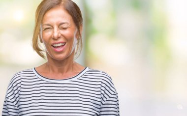 Orta yaş üst düzey İspanyol kadın seksi bir ifadeyle, neşeli ve mutlu yüzünü kameraya bakarak göz kırpıyor izole arka plan.