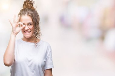 Güzel genç esmer kıvırcık saçlı kız gülümsüyor, parmakları ile mutlu yüz üzerinden seyir göz el ile ok jest yapıyor izole arka plan üzerinde gözlük.