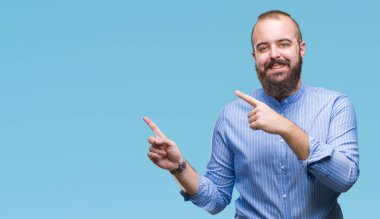 Genç beyaz hipster adam gülümseyerek ve iki elleri ve parmakları ile tarafına işaret kamera bakarak izole arka plan.