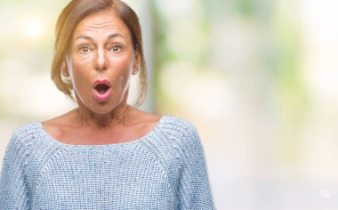 Orta yaş İspanyol kadın kıdemli giyen kış kazak korkuyor ve şok sürpriz ifade ile izole arka plan üzerinde korku ve yüz heyecanlı.