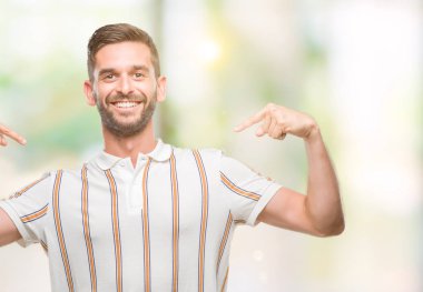 Yüzünde gülümseme ile kendinden emin görünüyorsun, kendini gururlu ve mutlu parmakları ile işaret izole arka plan üzerinde genç yakışıklı adam.