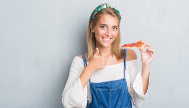 Grunge güzel genç kadın gri ok işareti, başparmak ile parmak, mükemmel işareti yapıyor kocaman bir gülümseme ile biberli pizza dilimi mutlu yemek duvar