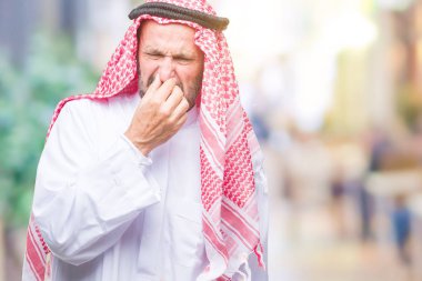 Keffiyeh bir şey pis ve iğrenç kokulu izole arka plan üzerinde dayanılmaz koku, holding nefes parmak ile burun üzerinde giyen üst düzey Arap adam. Kötü kokuyor kavramı.