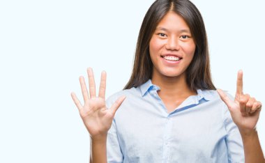 Genç Asyalı iş kadını gösterilen ve parmakları ile işaret izole arka plan üzerinde kendinden emin ve mutlu gülümseyerek süre yedi numara.