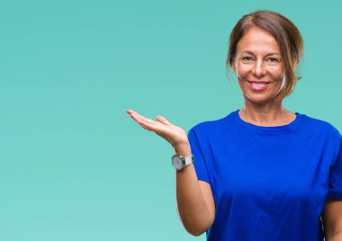 Orta yaş neşeli sunulması ve kameraya bakarak avucunun ile işaret gülümseyen izole arka plan üzerine İspanyol kadın kıdemli.