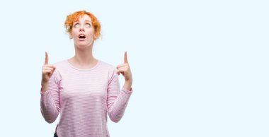 Genç Kızıl saçlı kadın hayrete ve yukarıya bakıp parmakları ile işaret şaşırttı ve silah kaldırdı.