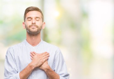 Yakışıklı delikanlı ile gülümseyen izole arka plan üzerinde kapalı gözler ve yüzünde minnettar jest ile göğüs üzerinde eller. Sağlık kavramı.