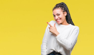 Genç izole arka neşeli bir gülümseme ile el ve parmak kadar kameraya bakarak yüzündeki mutlu ve doğal ifade ile yan ile işaret yüz üzerinden kış kazak giyen Afro-Amerikan kız saç örgülü.