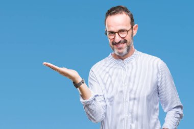 Orta yaş ağarmış komuta sizde neşeli sunulması ve kameraya bakarak avucunun ile işaret gülümseyen izole arka plan üzerinde gözlük.