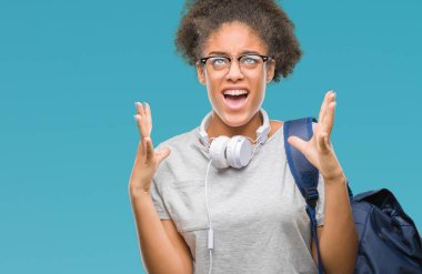 Üzerinde kulaklık ve sırt çantası giyen genç afro Amerikan öğrenci kadın arka plan deli izole ve deli bağırarak ve agresif ifade ve silah kaldırdı bağırıyor. Hayal kırıklığı kavramı.