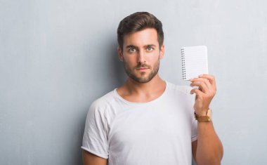 Acımak yüz ciddi düşünüyorum üstünde kendine güvenen bir ifade ile boş defter tutan gri grunge duvarın üzerinden yakışıklı genç