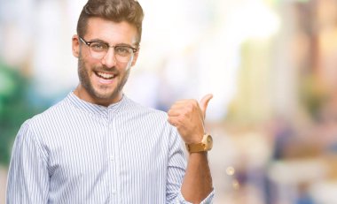 Yakışıklı delikanlı arıyor ve başparmak yanında yukarıyı mutlu yüz ile gülümseyen izole arka plan üzerinde.