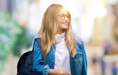 Üzerinde kulaklık ve gözlük giyen genç güzel sarışın öğrenci kadın arka plan uzak tarafına gülümseme ile yüzünde, doğal ifade arıyorum izole. Kendine güvenen gülüyor.