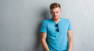 Kızgın ve korkmuş ağlıyor genç Kızıl saçlı adam rahat kıyafet depresif ve sıkıntı, endişe gri grunge duvarın üzerinden. Üzgün ifade.