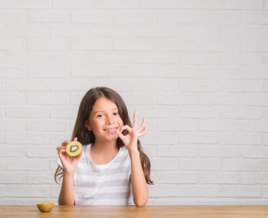 Parmak, mükemmel sembolü ile ok işareti yapıyor tablo yeme kivi oturan genç İspanyol çocuk