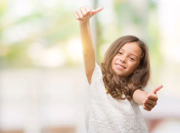 棕褐色的西班牙女孩赞成用手做积极的手势 竖起大拇指微笑 为成功而高兴 看着相机 胜利者的手势 — 图库照片
