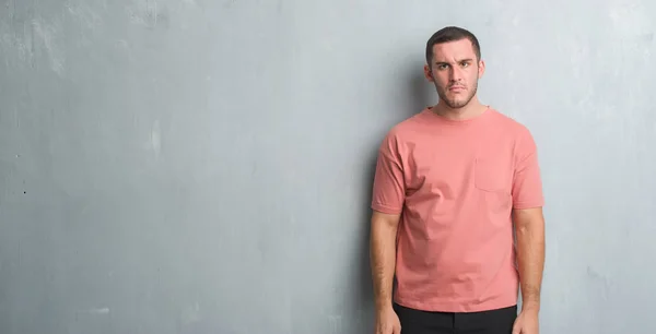 Joven Hombre Caucásico Sobre Gris Pared Grunge Escéptico Nervioso Frunciendo —  Fotos de Stock