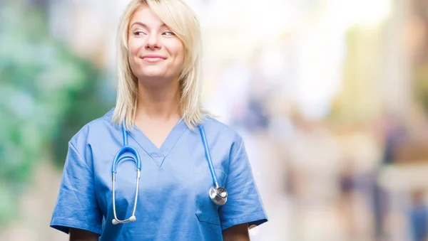 笑って見ている側と見つめて離れて思考孤立の背景に医療制服を着て美しい金髪女医女性 — ストック写真