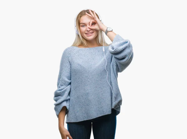 幸せそうな顔で指を通して見る目の手で のジェスチャーを行う分離の背景にヘッドフォンを着て音楽を聴く若い白人女性 — ストック写真