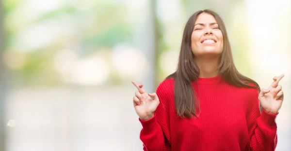 Joven Hermosa Hispana Vistiendo Suéter Rojo Sonriendo Cruzando Los Dedos — Foto de Stock